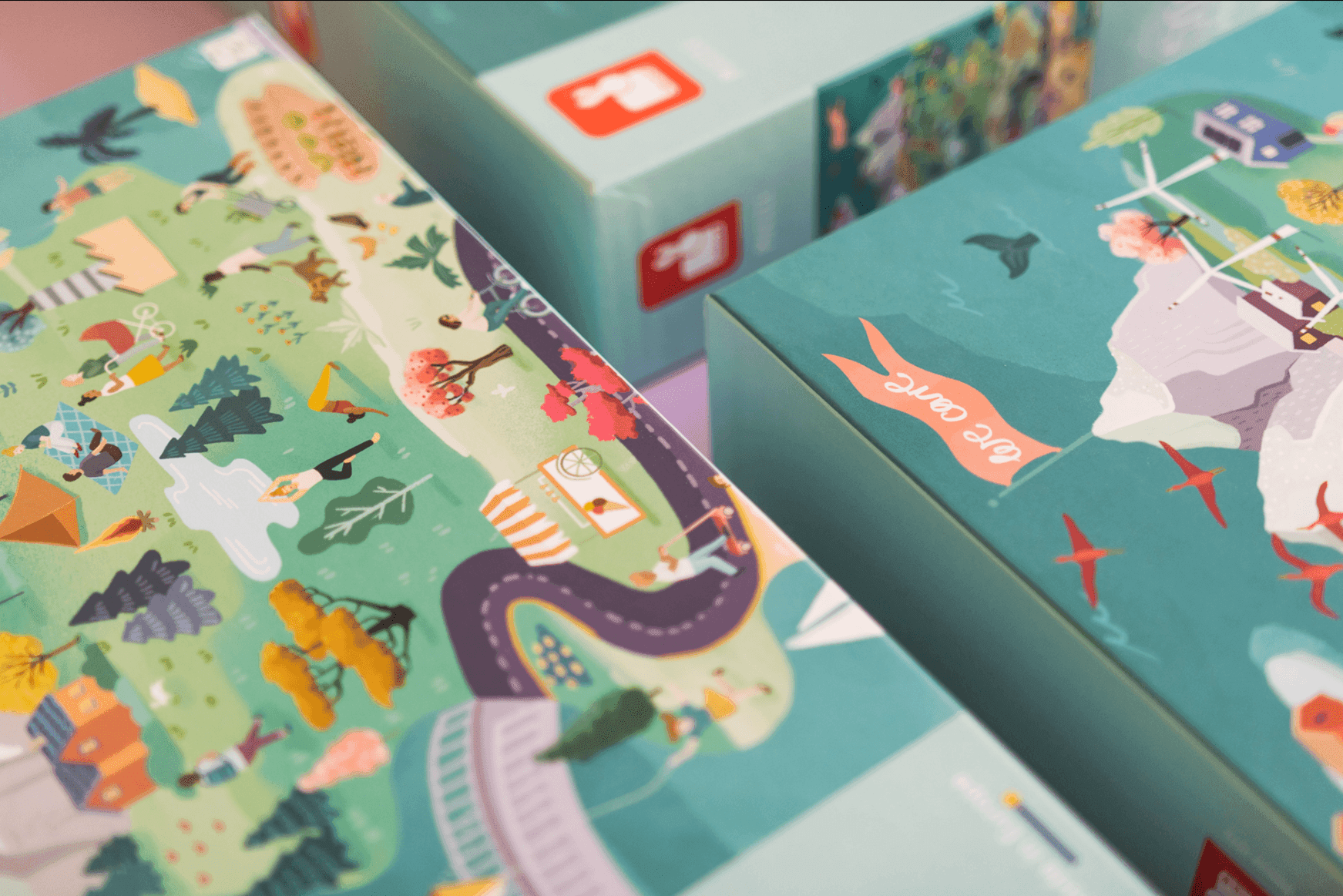 Colorful illustrated map on board game packaging showing outdoor scenes, people, trees, and pathways.