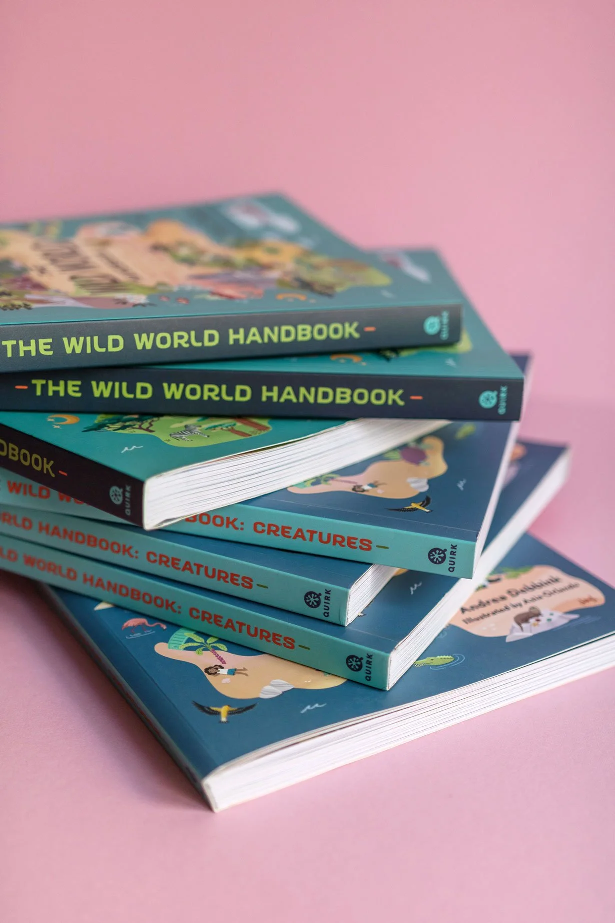 Stack of children's books about animals and the wild, with colorful illustrations, placed on a pink background.