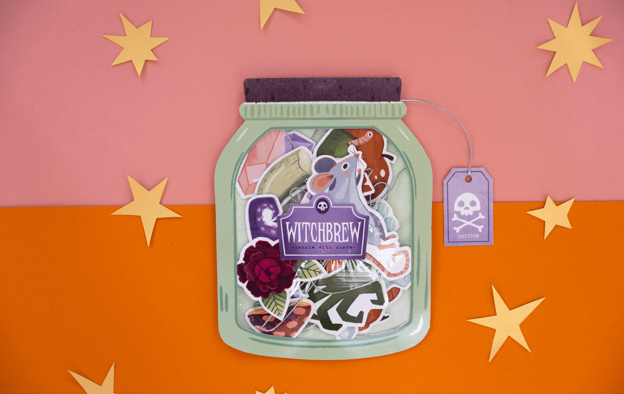 Witchbrew Halloween garland card by Asia Orlando, featuring a jar-shaped illustration with bewitching ingredients including a frog, dried roses and crystals.